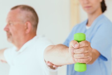 Physiotherapist assisting a senior patient performing weight exercises