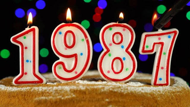 Birthday cake with white burning candles in the form of number 1987