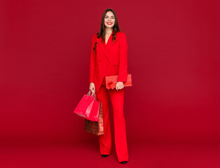 attractive woman in red with shopping bags sale on red background