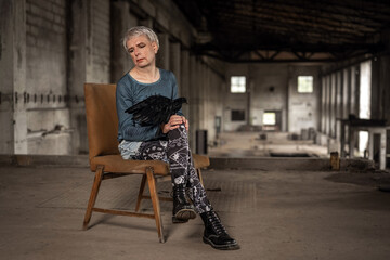 Mensch mit Raben auf dem Schoß blickt sinnierend nach unten