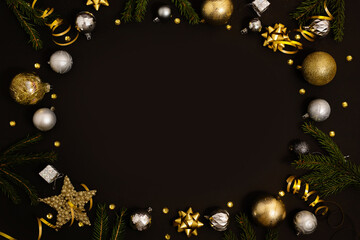 Christmas background with fir branches, gold decorations and pine cones on a black table. Flat lay. top view with copy space