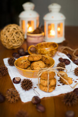  Homemade oatmeal cookies in yellow clay plate on white embroidered napkin against the background of candlesticks