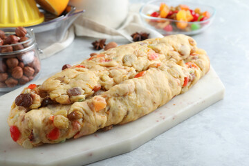 Unbaked Stollen with candied fruits and raisins on light marble table, closeup