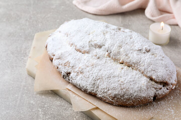 Fototapeta na wymiar Delicious Stollen sprinkled with powdered sugar on light table, closeup