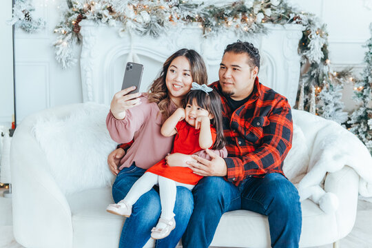 Asian family father, mother with daughter toddler girl celebrating Christmas or New Year and taking selfie photo for social media