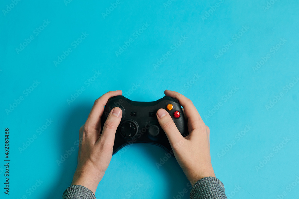 Wall mural hands of a man holding a video game console controller on a blue background