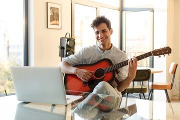 young hispanic man playing guitar. music lesson with a tutorial