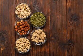 Obraz na płótnie Canvas Pistachios, hazelnuts, peanuts, pumpkin seeds, cashews on a wooden table. Portions of nuts on a wooden table. Assorted nuts. Nut diet.