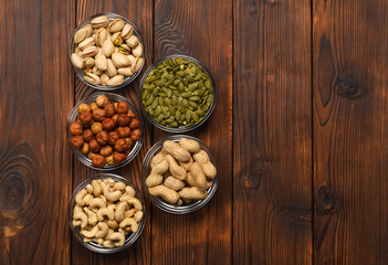 Pistachios, hazelnuts, peanuts, pumpkin seeds, cashews on a wooden table. Portions of nuts on a wooden table. Assorted nuts. Nut diet.