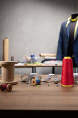 Thread spool and needle with sewing tools on table. Concept of clothes atelier workplace
