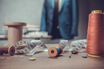 Thread spool and tape measure with sewing tools on table. Concept of clothes atelier workplace