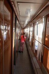 Odessa, Ukraine - 10|18|2020: Child girl is having fun inside a compartment carriage in the corridor. The sun is pouring into the windows of the carriage. Interior of old passenger cars