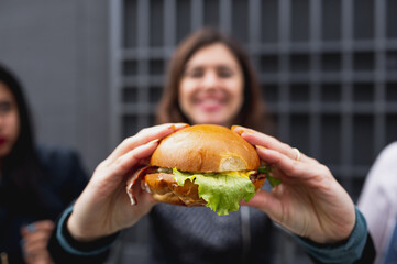 Close-up vegan burger. Smiling blurred woman on background holding hamburger.