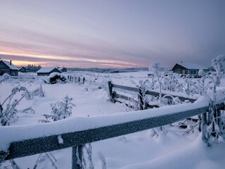 Winter landscape overlooking the outskirts of the village.  Wooden hedge in the snow in the foreground