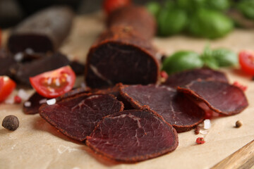 Delicious dry-cured beef basturma with spices on wooden table, closeup