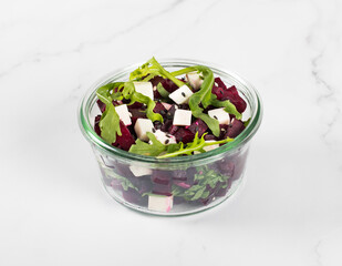 Appetizer. Beetroot, cottage cheese, arugula salad with black and white sesame seeds in a glass salad bowl on a white background