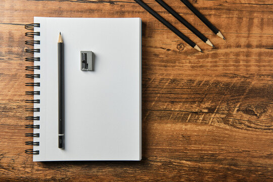 Concepto de dibujo para arquitectura y dise&ntilde;o, mano realizando bocetos, herramientas para dise&ntilde;o y dibujo sobre fondo de madera.