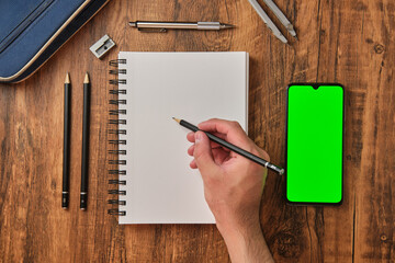 Concepto de dibujo y deseño con pantalla verde, lapices de trazado y cuaderno para bocetos sobre fondo de madera desde una vista cenital. 