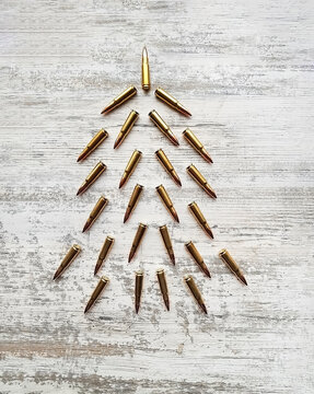 Postcard with an Christmas tree in military style made of cartridges for AK 47. Concept Military tree made of cartridges on a white wooden background. Flatley from cartridges for the New Year.