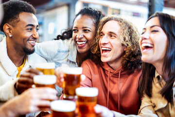 Multicultural hipster friends drinking and toasting beer at brewery bar restaurant - Beverage life style concept with guys and girls having fun together - Bright filter with focus on right guy