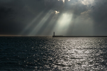 Muelle con faro en altamar con cielo tormentoso