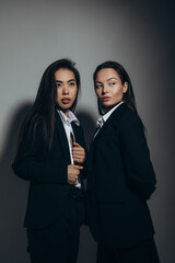 Two young brunette women pose in studio.