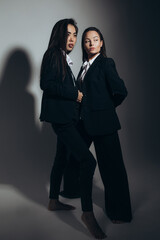 Two young brunette women pose in studio.