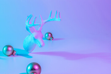 Christmas animal neon winter background. Holiday decoration bauble ball on neon gradient backdrop. Minimal abstract xmas reindeer. Happy new year copy space.