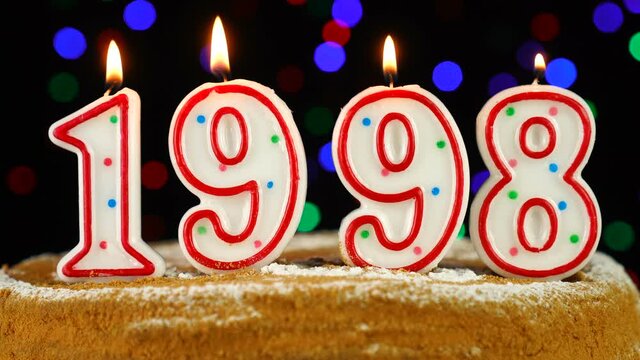 Birthday cake with white burning candles in the form of number 1998