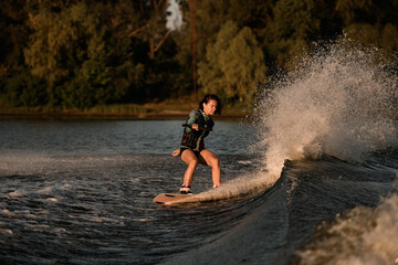 view of attractive woman holding rope and rides down the wave on wakeboard