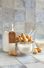 Vegan potato milk in glass and potato on ceramic tile background. Plant based milk replacer, lactose free concept. Selective focus, close up