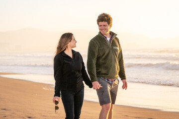 young couple in love walking on the beach holding hands happy