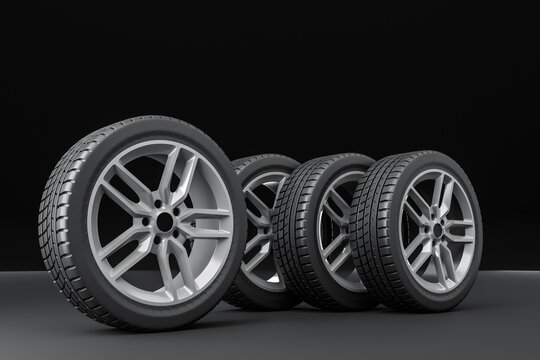 Four car tires stacked on a black background