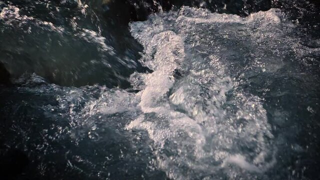 Slow motion of wild clear mountain river , stream flowing through rocks. Close up of river stones with flowing water, clean water flowing in a mountain river