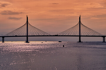 Cable-stayed bridge over the river at sunset. Water landscape.