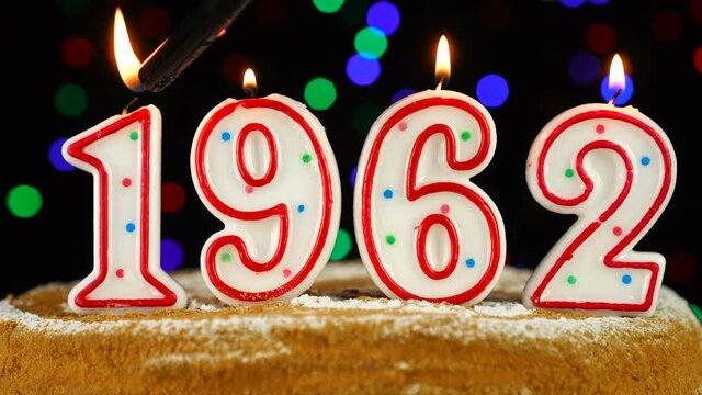 Birthday cake with white burning candles in the form of number 1962