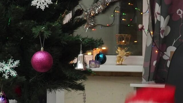 Family decorating a Christmas tree with boubles in the living room. mom and daughter decorate the tree with different toys home, family holidays, happy new year and christmas