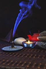 Incienso encendido con humo azul en un fondo oscuro