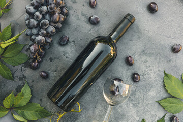 Bottle of red wine, green vine, wineglass and ripe grape on vintage dark stone table background. Top view copy space for text. Wine shop wine bar winery or wine tasting concept