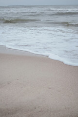 Sea foam and wave at the sandy shore. Baltic Sea in winter. Atmospheric concept for your design