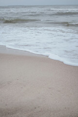 Sea foam and wave at the sandy shore. Baltic Sea in winter. Atmospheric concept for your design