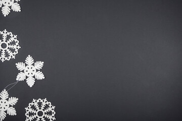 White Christmas tree toys in the form of snowflakes lie on a black background. Christmas card mockup