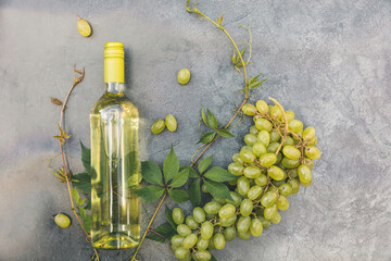 Top view of bottle white wine, green vine and ripe grape on vintage gray stone table background....