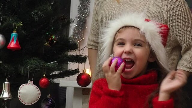 Family decorating a Christmas tree with boubles in the living room. mom and daughter decorate the tree with different toys home, family holidays, happy new year and christmas