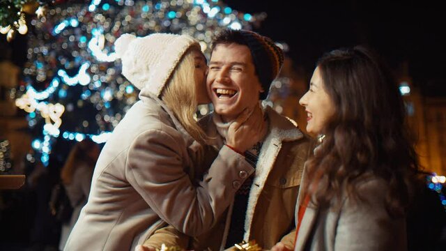 three friends with gifts at christmas night at old town square. Friendship, christmas, new year, holiday concept. New York