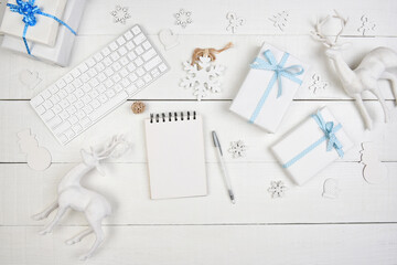 Flat Lay Christmas Concept. White paper wrapped Presents with blue ribbon a blank note pad and Computer keyboard for cyber shopping.