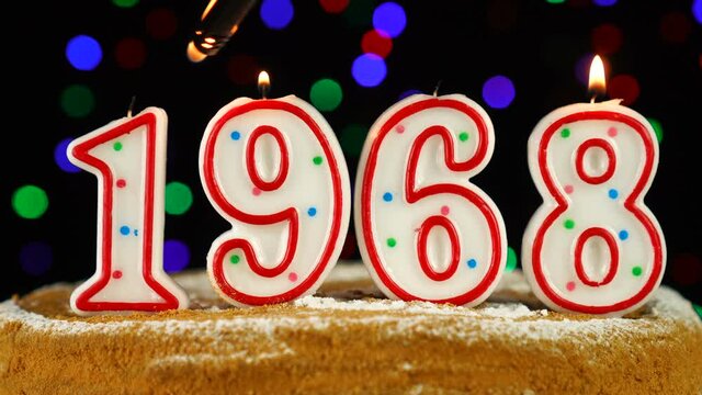 Birthday cake with white burning candles in the form of number 1968