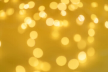 Defocused yellow background. Festive Christmas background from a glowing garland with many lights. New Years celebration concept.