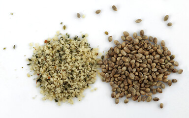 Two heaps of raw hemp seeds, whole and shelled, on a white background.