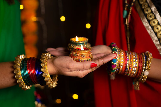 Woman hand's with bangles holding Diya 